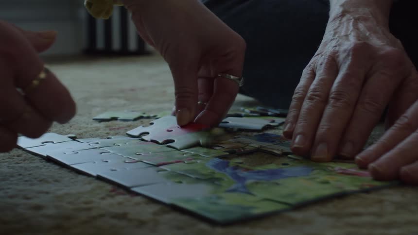 Mother and daughter assembling a puzzle over the rug in the living room