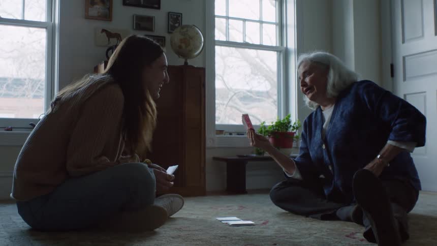 The old woman and the young woman playing spades on the carpet in the living room