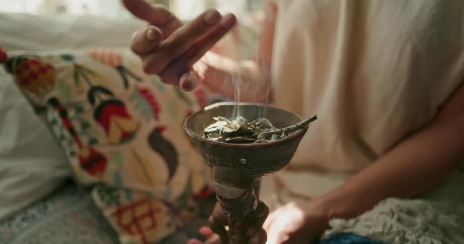 Native american woman burning sage in incense burner moving hand around smoke