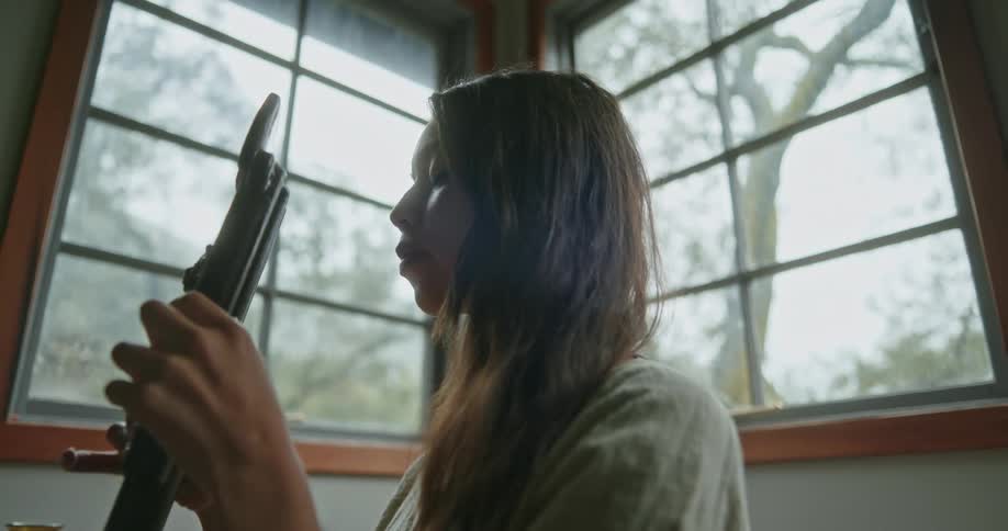 A woman is sitting indoors and playing an instrument
