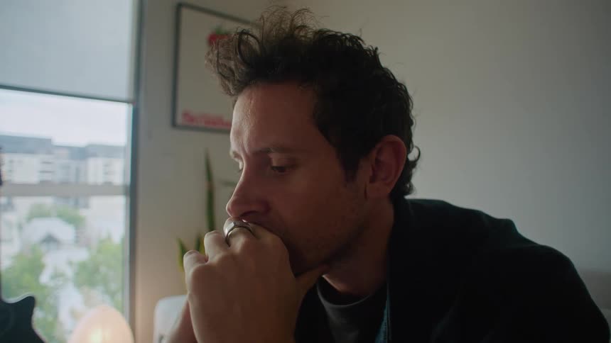 A close up of a mans camera and laptop and his face as eh smiles and thinks to himself