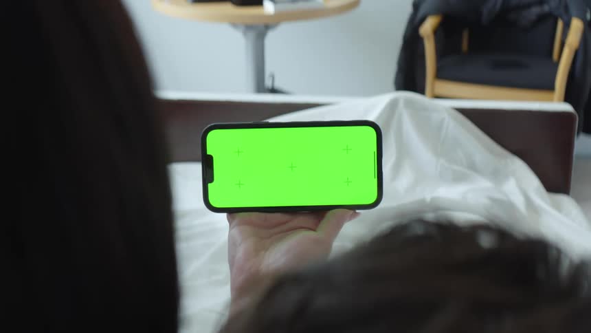 An up close of a persons hand holding a cell phone in front of another person