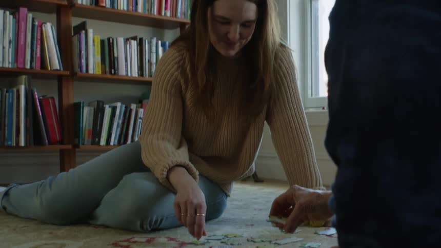 A younger woman and an older woman sitting on the floor putting a puzzle together