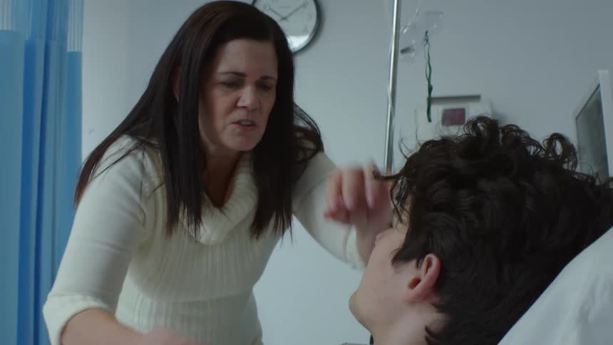 Mother standing over son in observation unity in hospital she is very worried about him