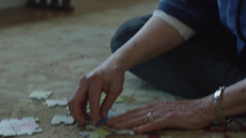 Woman with long white hair sitting on the living room floor assembling a puzzle
