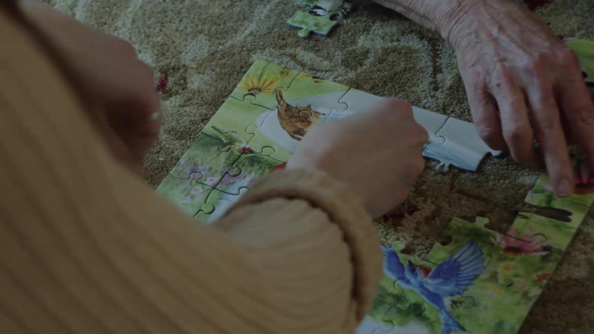 Two people are putting together a puzzle indoors