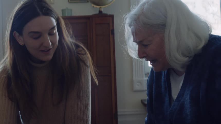 A young woman sits on the floor with her grandmother