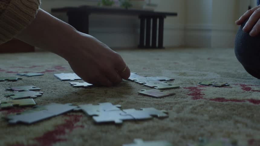 Two people are putting a puzzle together on the ground