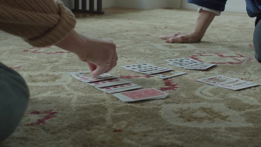 Two people are sitting down and playing a card game