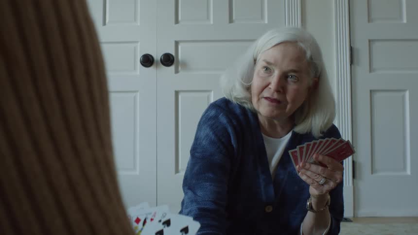 Two women are sitting on the floor talking as they play a game of cards