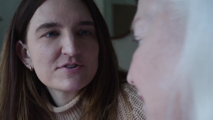 A woman and an elderly man sit next to each other and have a conversation