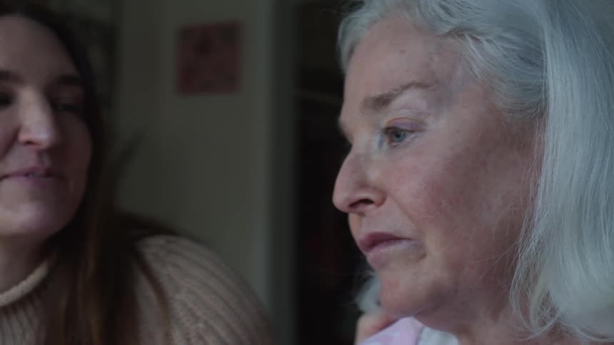 Close up of the face of an elderly woman talking to a younger relative at home