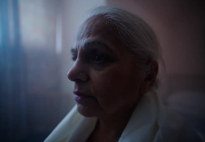 A portrait of an elderly woman sitting in a room