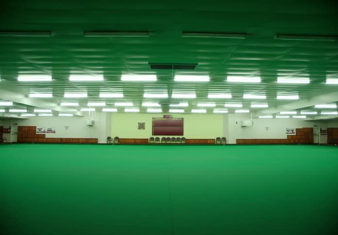 Lights turning on over the bright green carpet of a large meeting hall