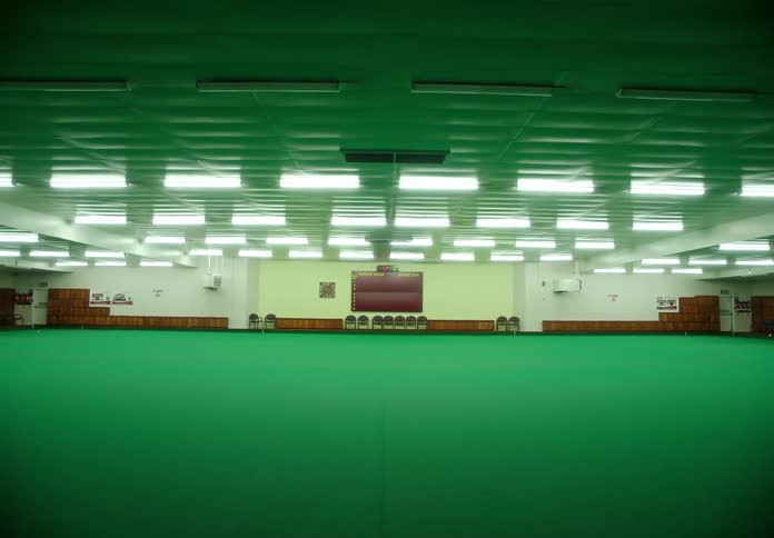 Lights turning on over the bright green carpet of a large meeting hall