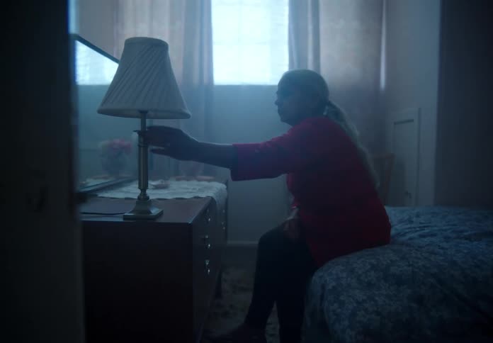 A woman turns off her bedroom lamp while crying