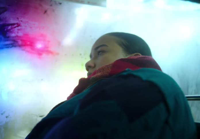 Close up of the face of a woman riding a bus on the city at night