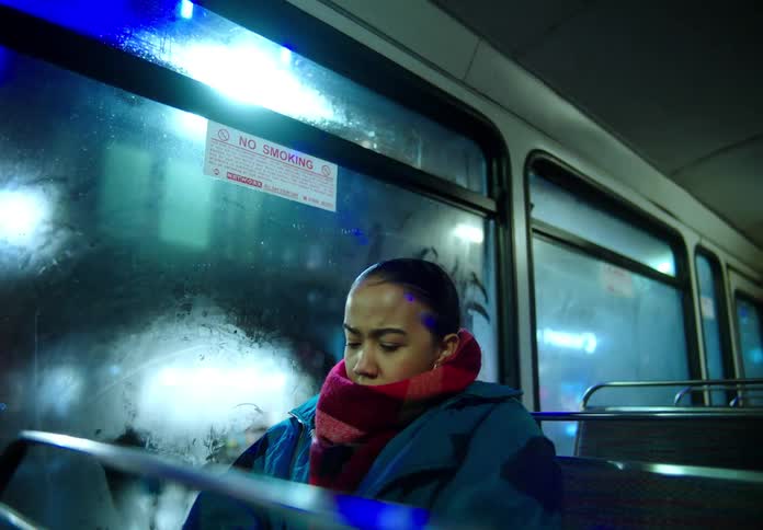 Young woman riding a city bus at nighttime looking out the window
