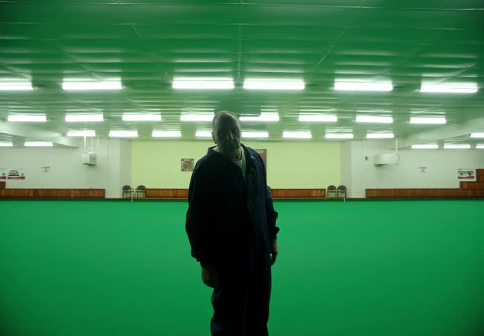 Silhouette of the face of a sad man standing on the green rug of a large dance room