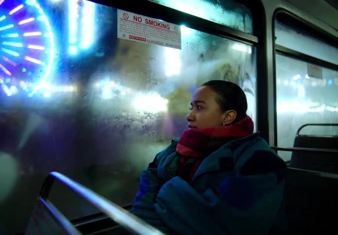 Woman with red scarf and blue jacket travels on bus at night