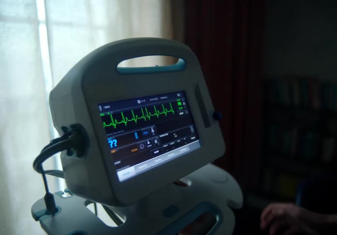 The green graph lines on a hospital machine are moving as a persons hand touches it