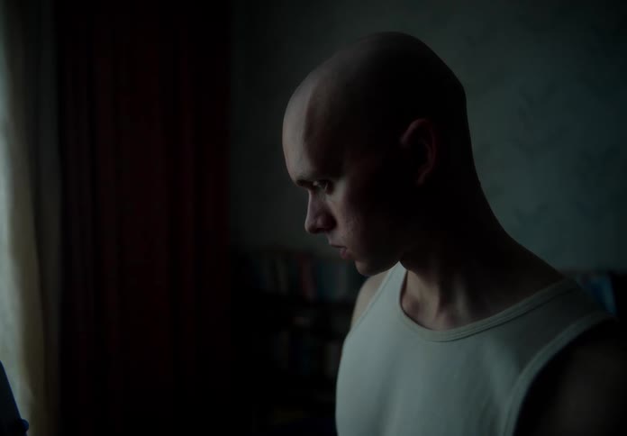 A young bald man stands and checks a device used to monitor vital signs