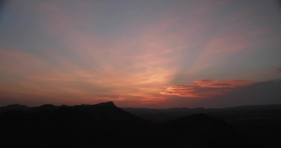 Clouds are colored by the sunset over peaks