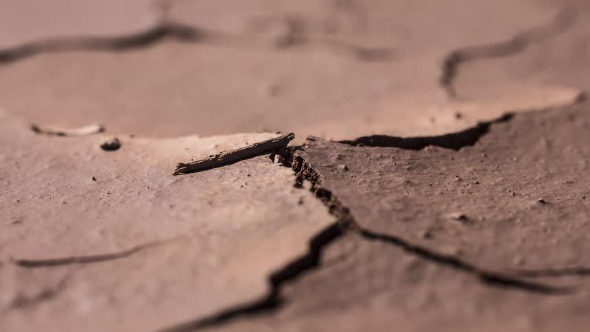 Dry and cracked land brightens as the sun comes up