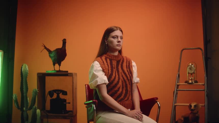 A portrait of a woman sitting in an orange room