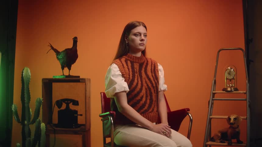 A woman poses on a set make to look like a room