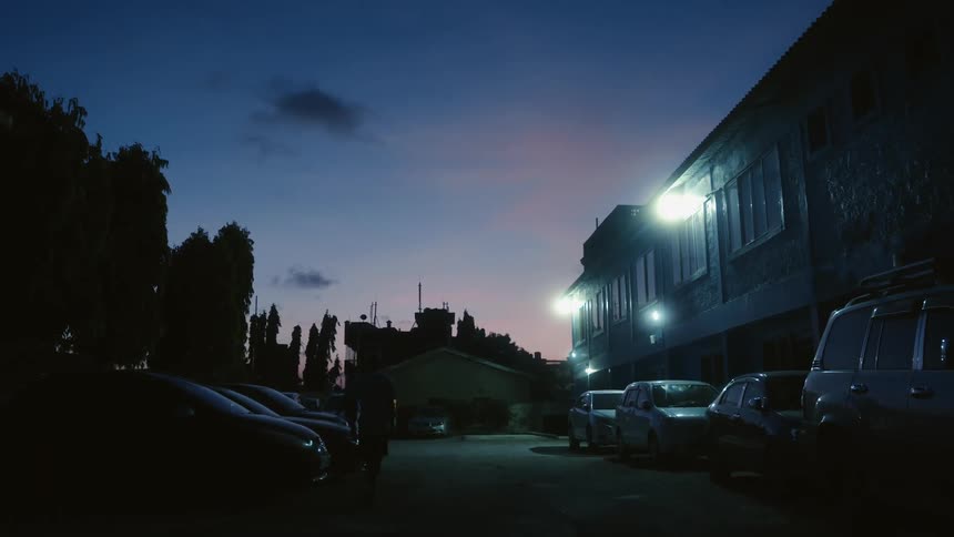 Two people walk towards a car located in a residential parking area