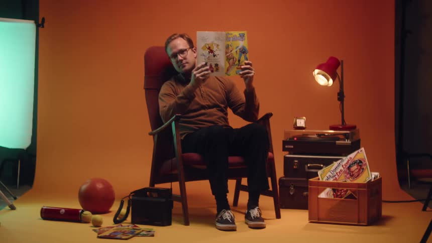 A young man is sitting down and reading a magazine