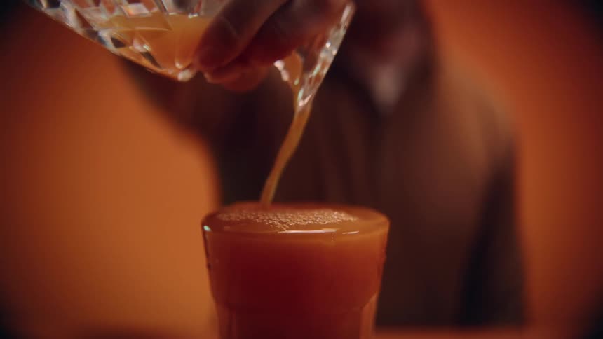 A person is pouring beverage into a glass
