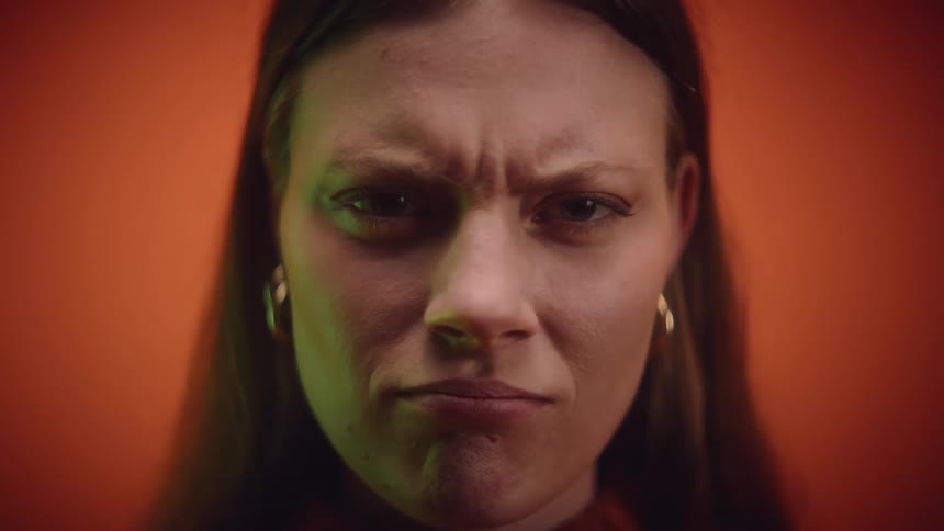 A close up of a womans face as she changes her expression from frowning to smiling to scowling