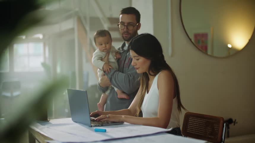 A mother is typing on a computer and talking to her family