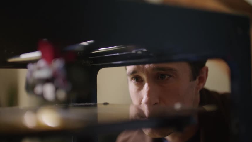 A close up of a robot like machine moving around as a man watches it up close