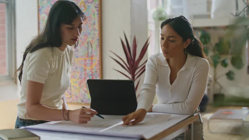 Businesswomen with white shirts working on plans at table