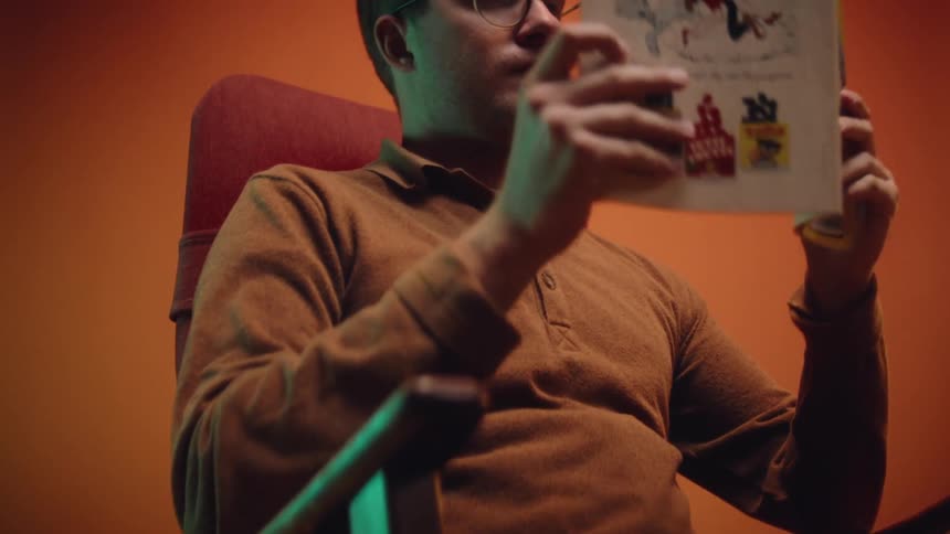 The view is of a man sitting down and reading a magazine
