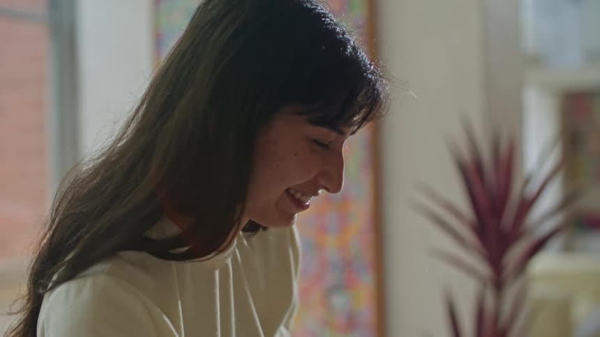 Women wearing white works on plan and laptop in room smiling talking with each other