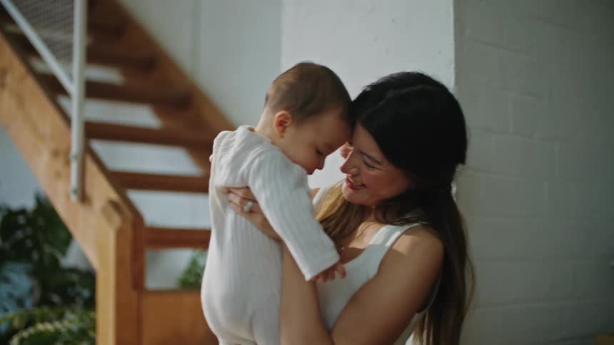 Mother and father at home with infant baby holding kissing and smiling at baby
