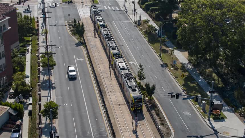 A train moves through town as cars pass on the street