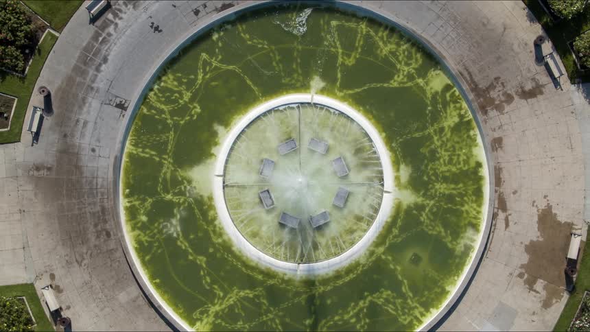 Benches decorate path surrounding circular fountain in park