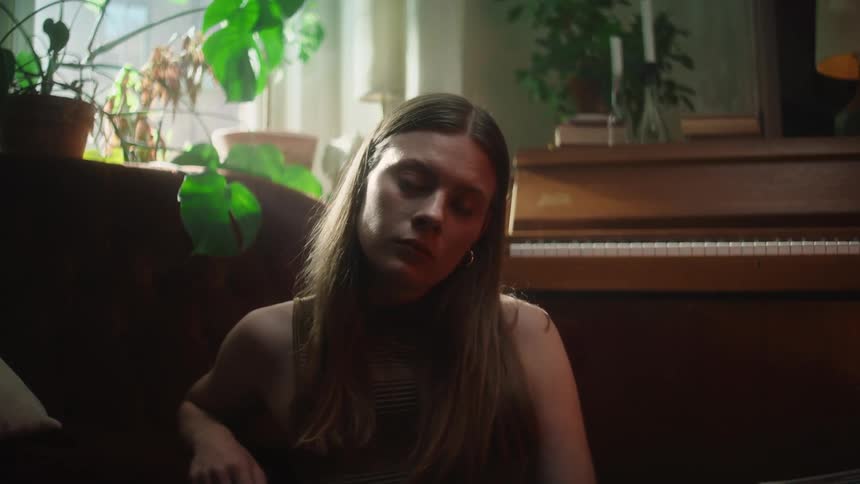 Portrait of a woman sitting near a piano during midday