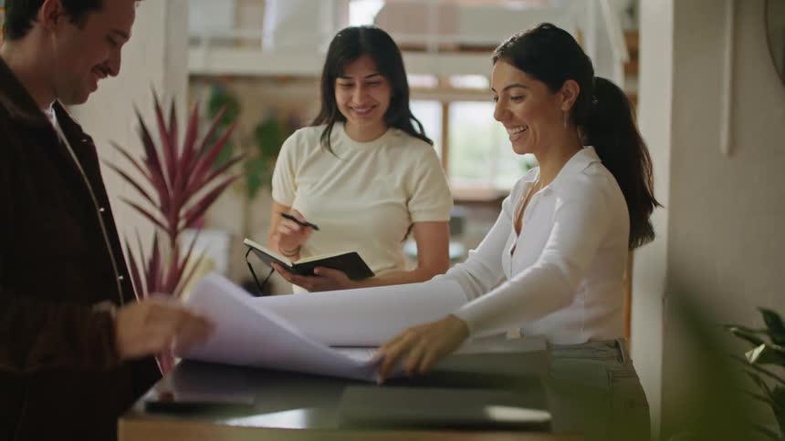 Coworkers examine blueprints while one takes notes
