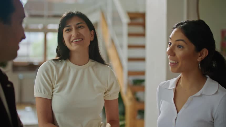 Man with brown jacket and mustache talks with women wearing white shirt