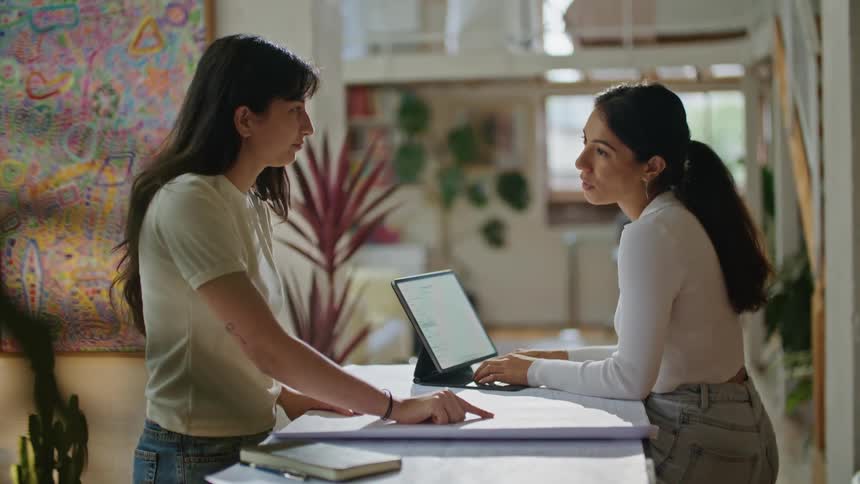 Two co workers are working together inside in the middle of the day
