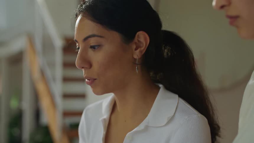 A close up of a woman writing on construction plans and talking to a person next to her