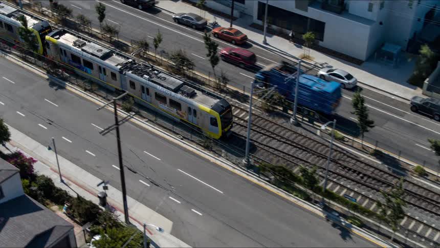 The view is of a train and cars driving down the road