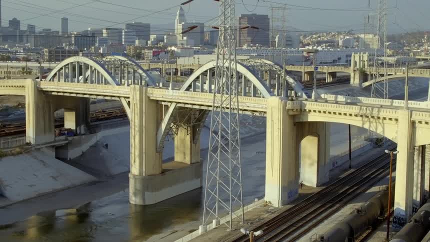 Cars are driving on a bridge in a downtown city