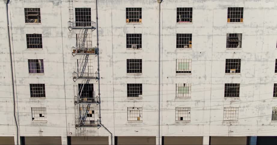 An aerial of a run down building with multiple windows and fire escapes